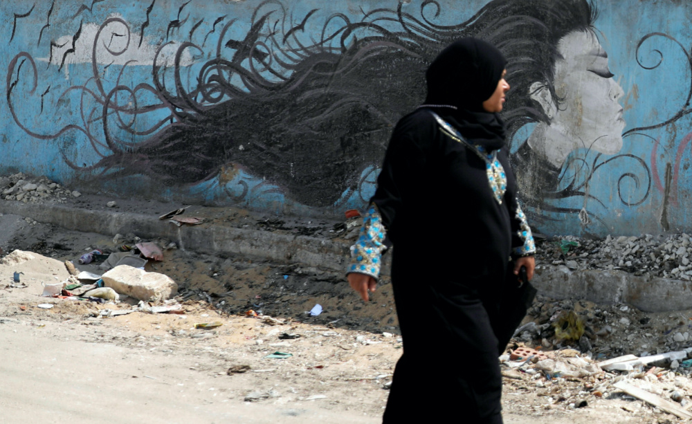 Woman walking past a mural in Cairo