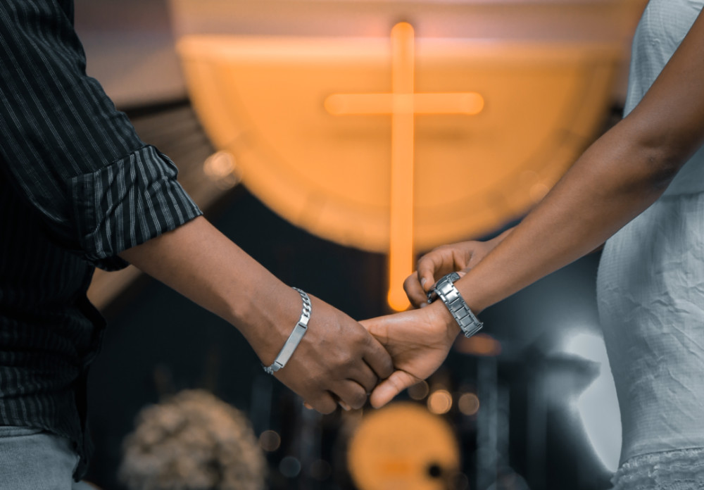Holding hands before a cross