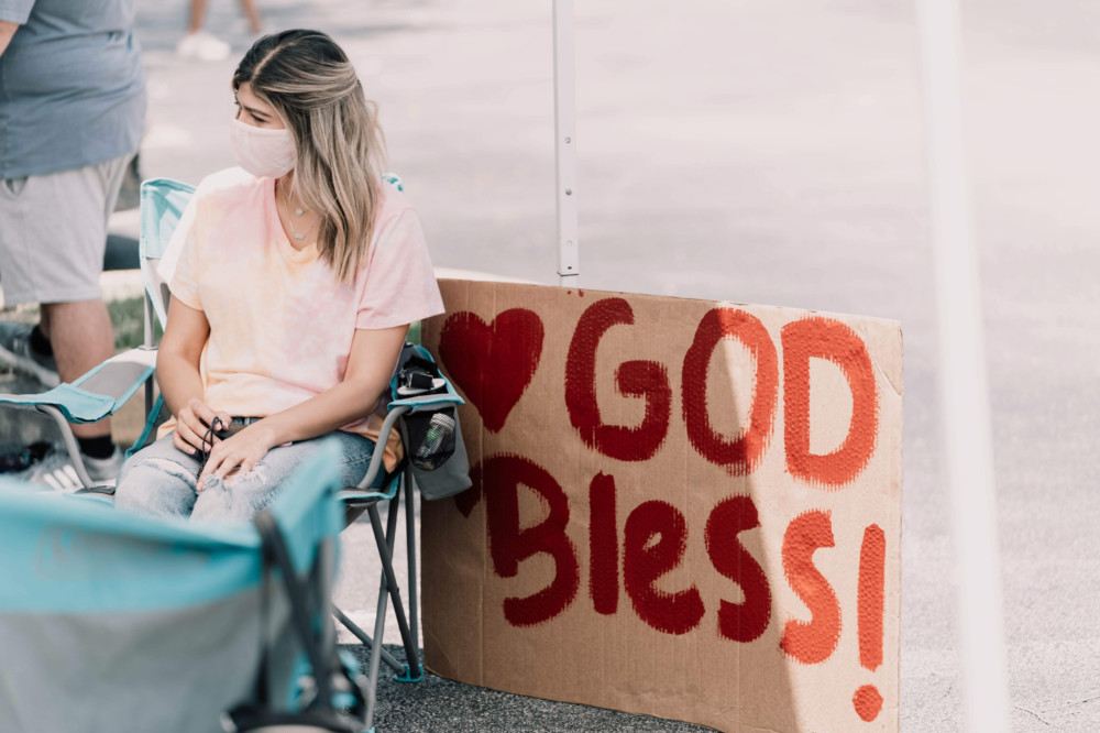 Woman and God Bless sign