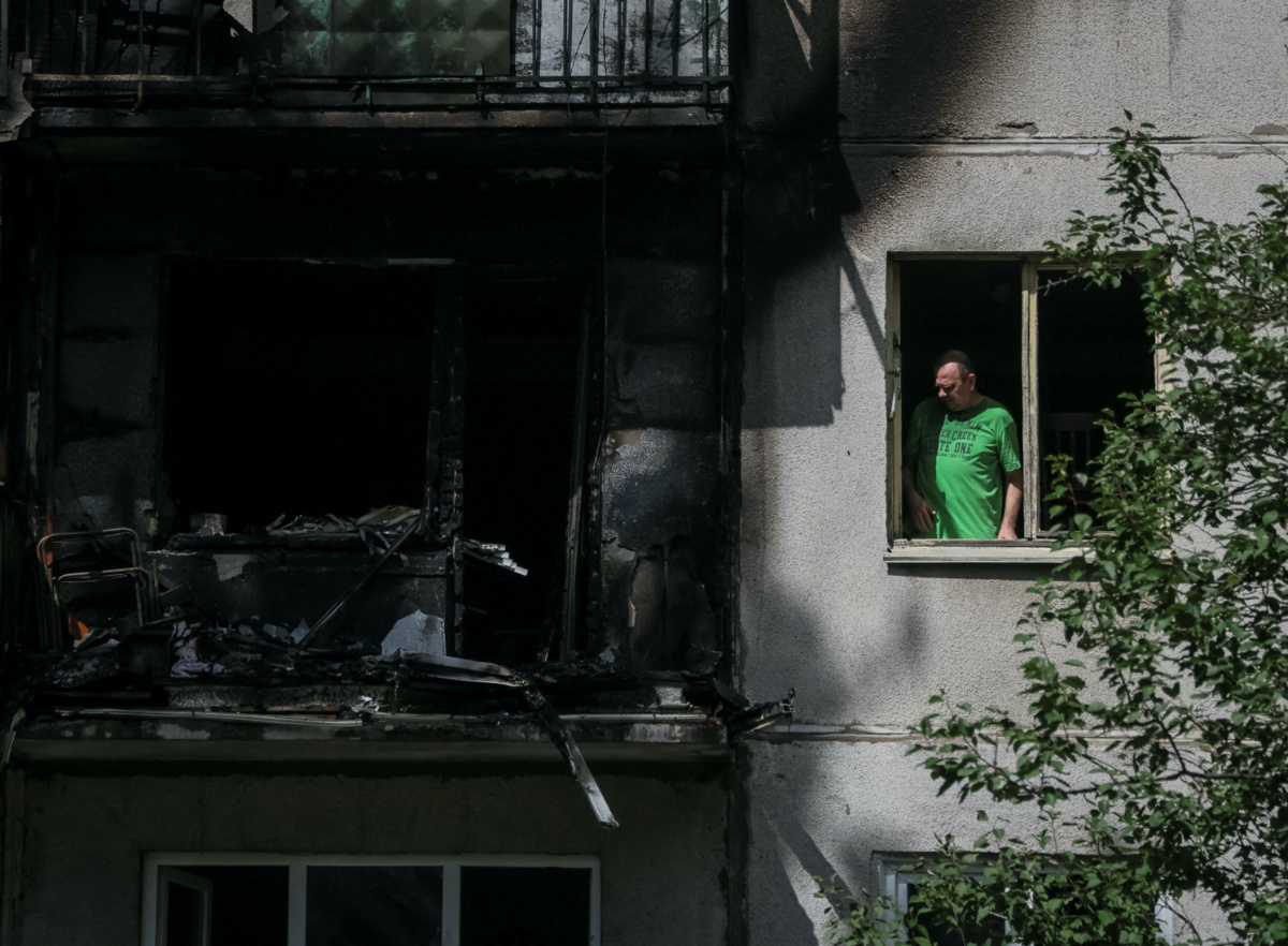 Ukraine Kramatorsk resident looks out window of damaged building
