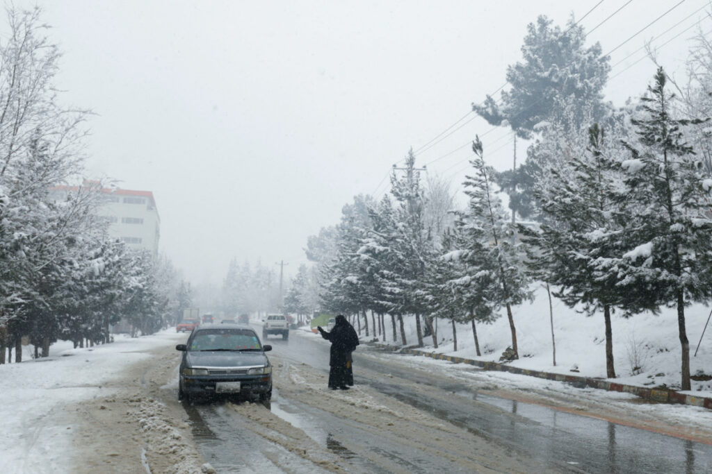 FILE PHOTO: An Afghan woman begs on a snowy day in Kabul, Afghanistan, January 29, 2023. REUTERS/Ali Khara