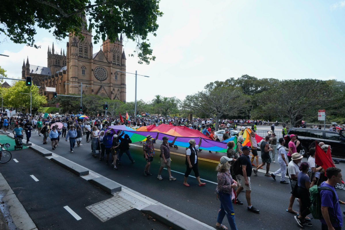 Sydney-based gay rights group Community Action for Rainbow Rights carry a large rainbow flag as the funeral and interment of polarizing Cardinal George Pell is under way at St. Mary's Cathedral in Sydney, Thursday, Feb. 2, 2023. Pell, who died last month at age 81, spent more than a year in prison before his sex abuse convictions were overturned in 2020. (AP Photo/Rick Rycroft)