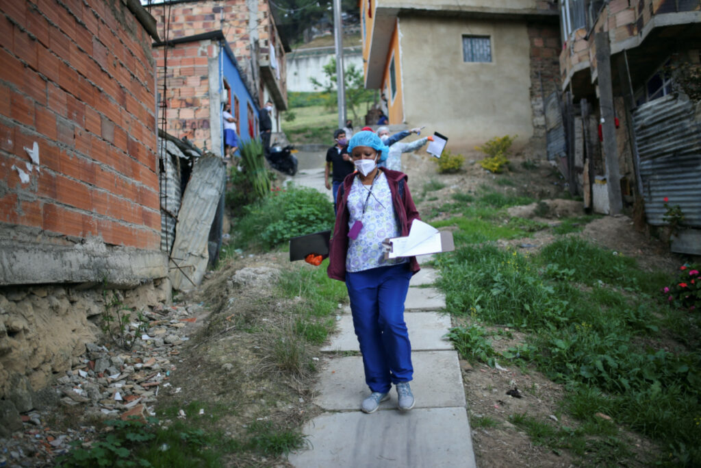 FILE PHOTO: Mayoral employees walk through a poor neighborhood during a day of food aid delivery, amid the outbreak of the coronavirus disease (COVID-19) in Bogota, Colombia April 21, 2020. REUTERS/Luisa Gonzalez