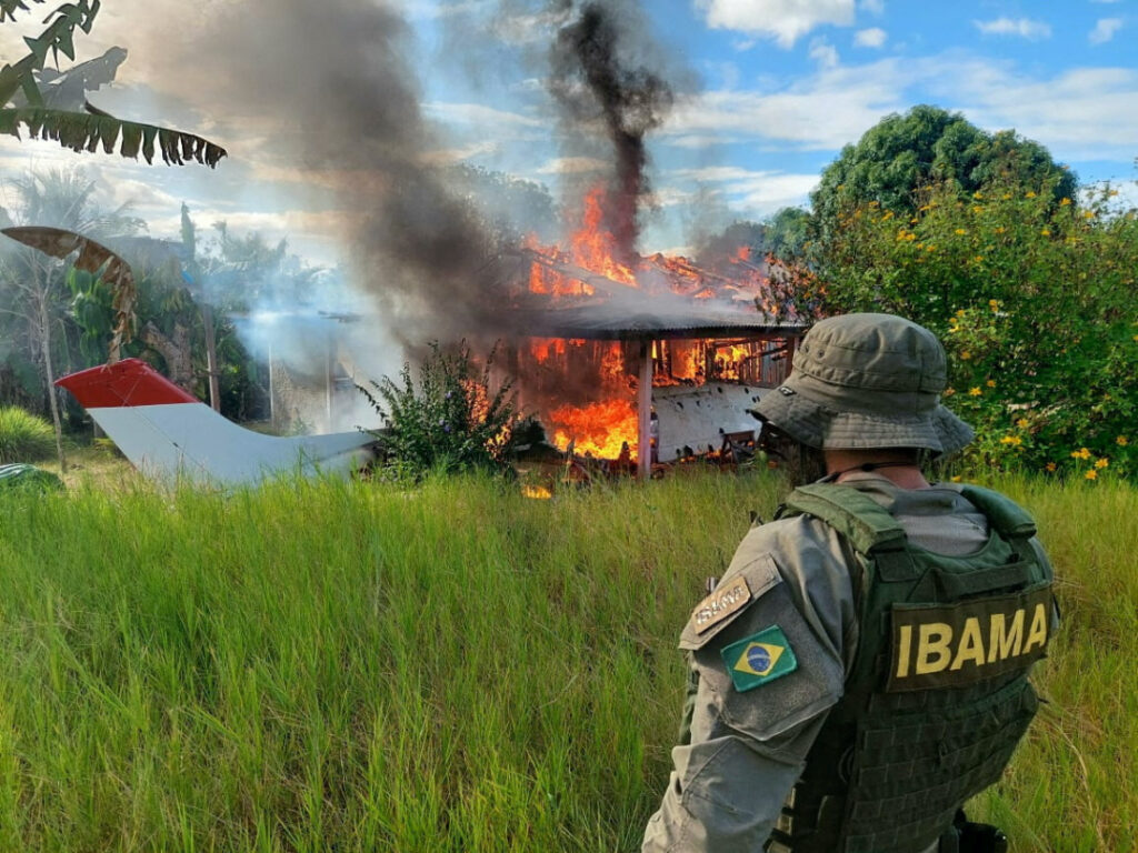 An agent of the Brazilian Institute for the Environment and Renewable Natural Resources looks on as a plane and a house belonging to miners are destroyed during an operation conducted jointly within Brazil's National Indian Foundation and Brazilian National Public Security Force against illegal mining in Yanomami indigenous land in Roraima state, Brazil February 6, 2023.