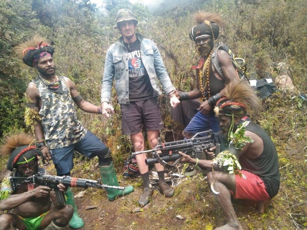 A man, identified as Philip Mehrtens, the New Zealand pilot who is said to be held hostage by a pro-independence group, stands among the separatist fighters in Indonesia's Papua region, in this undated picture released on February 14, 2023. 