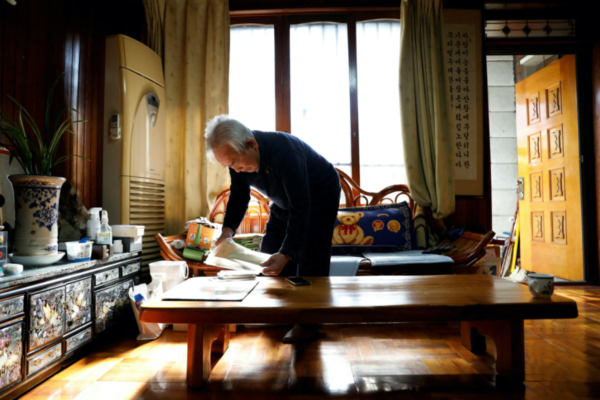 FILE PHOTO: Jeon Seok-ho, whose father died in the Chosei Coal Mine Disaster of 1942, prepares old photos of his family, during an interview with Reuters at his home in Daegu, South Korea, February 4, 2023.   REUTERS/Soo-hyeon Kim