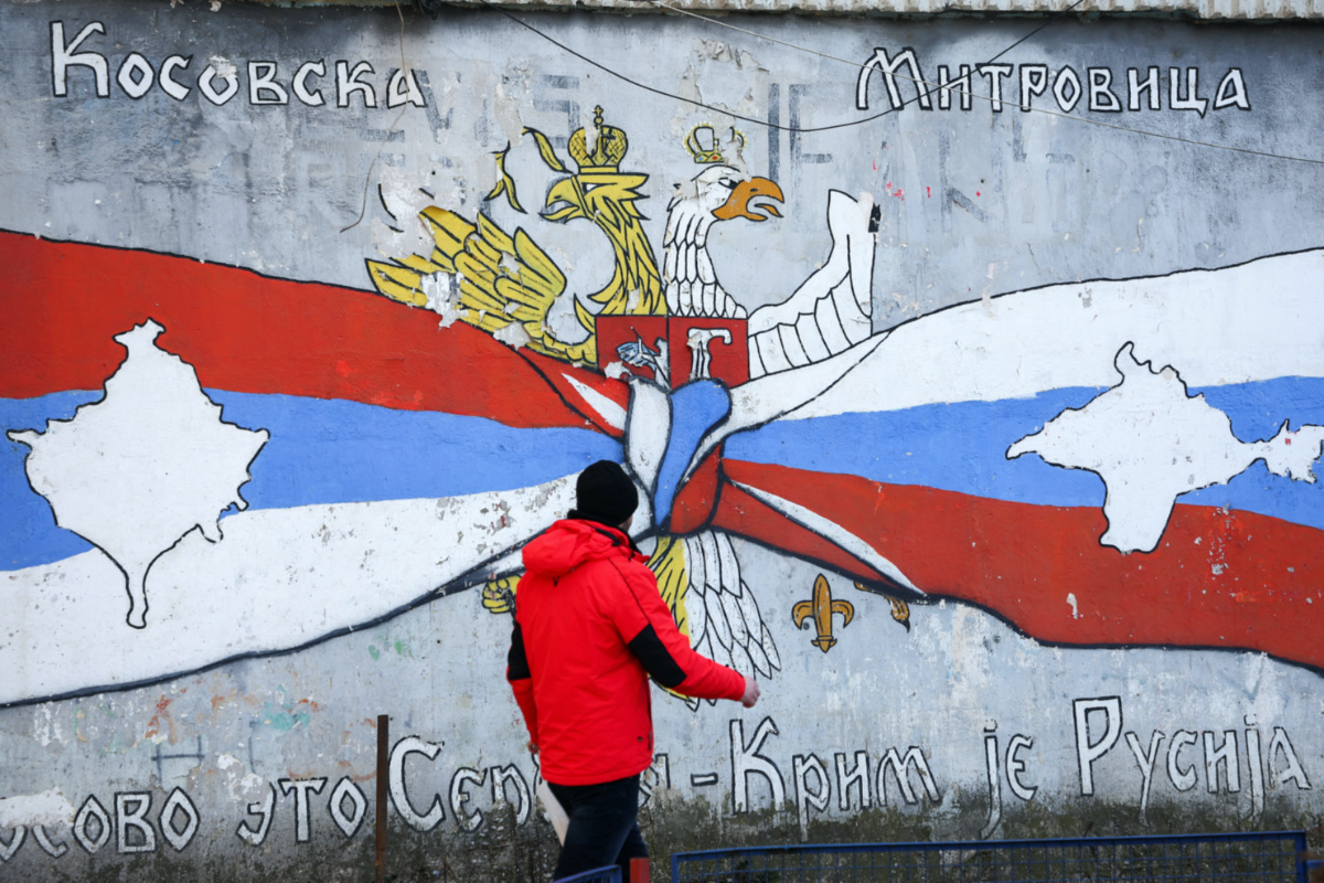 A person walks past a graffiti in the northern part of the ethnically-divided town of Mitrovica, Kosovo, February 6, 2023. REUTERS/Florion Goga