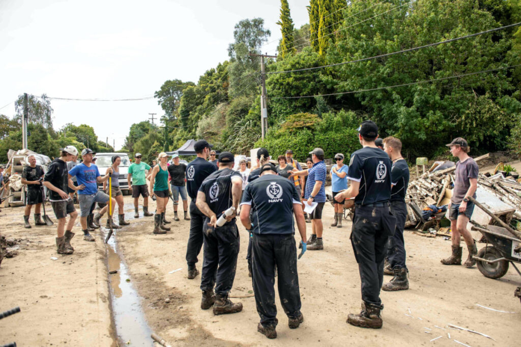HMNZS Te Mana crew members help with a clean up after a small creek bursts its bank causing houses to flood in Havelock North, New Zealand, February 18, 2023.