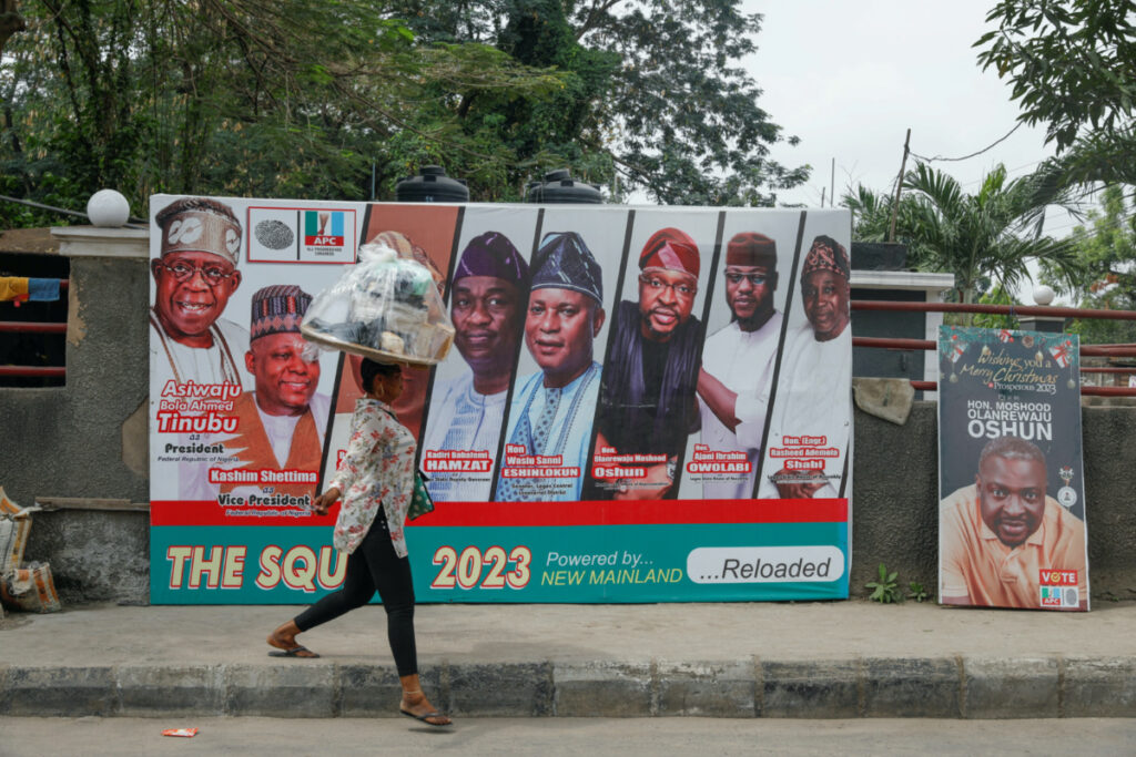 A woman hawks bread past electoral campaign posters, ahead of Nigeria's Presidential elections, in Lagos, Nigeria January 31, 2023.