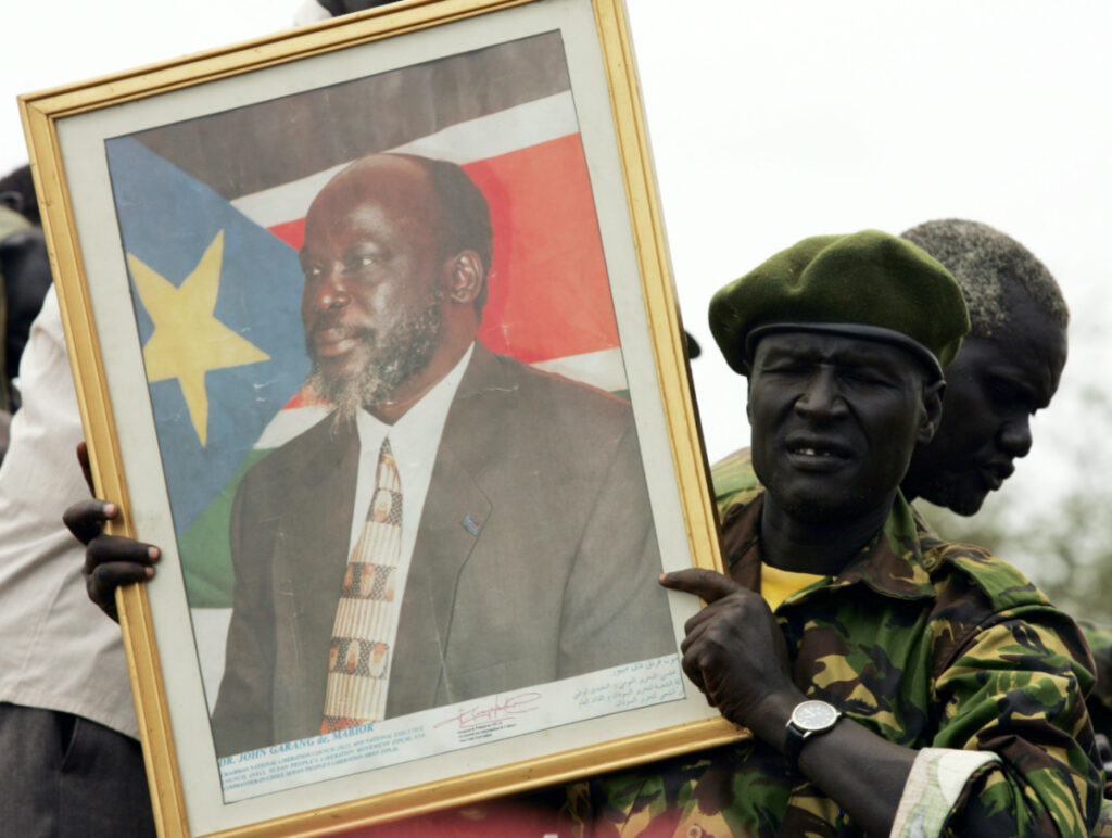 FILE PHOTO: A soldier holds a portrait of the late former Sudan People's Liberation Army/Movement (SPLA/M) leader John Garang at the New Site village in southern Sudan August 4, 2005. REUTERS/Radu Sigheti