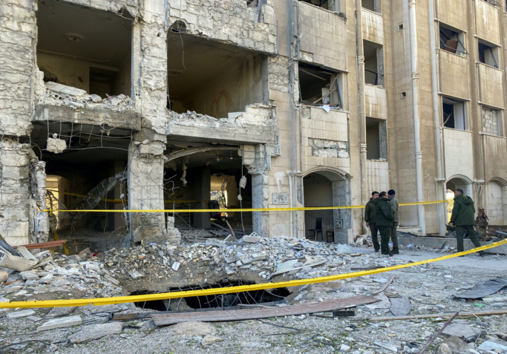 Police officers stand near a damaged building at the site of a rocket attack, in central Damascus' Kafr Sousa neighborhood, Syria, February 19, 2023.