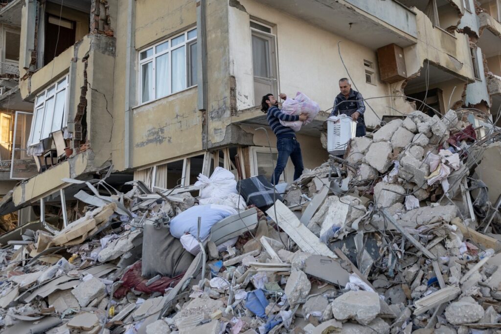 Arsin and his father take belongings out of their destroyed apartment in the aftermath of the deadly earthquake in Antakya, Hatay province, Turkey, February 20, 2023.