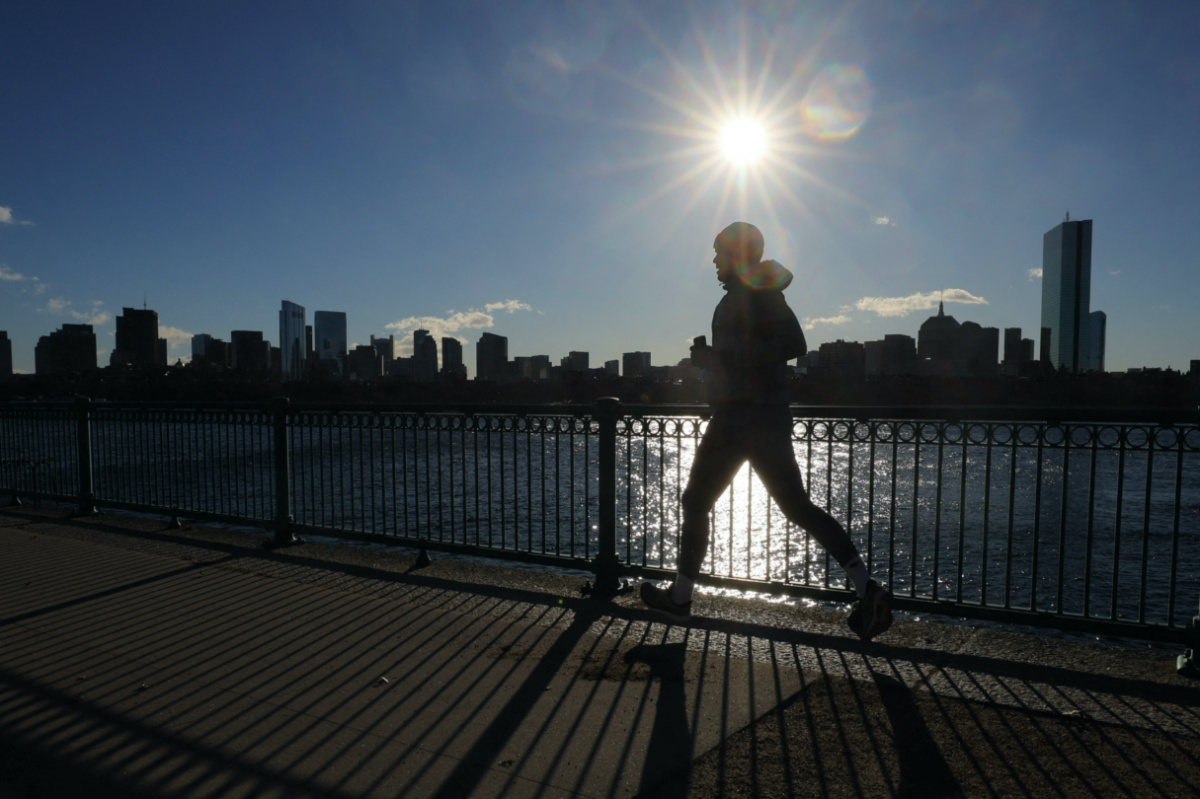A jogger runs along the Charles River, with the Boston skyline visible in the background, on a cold winter morning in Cambridge, Massachusetts, U.S., February 3, 2023. REUTERS/Brian Snyder