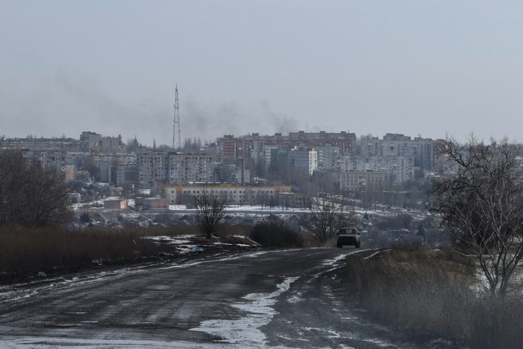 Smoke rises after a shelling as a car moves along a road in the frontline city of Bakhmut, amid Russia's attack on Ukraine, in Donetsk region, Ukraine February 19, 2023.