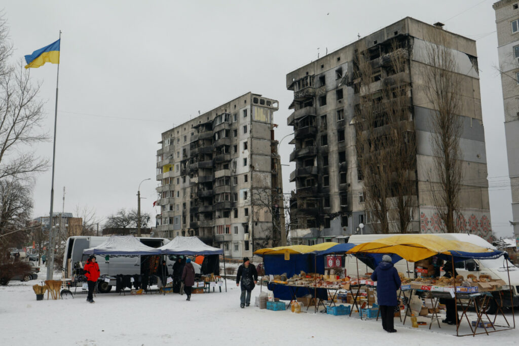 Local residents buy food at a street market in front of apartment building heavily damaged in the beginning of Russia's attack on Ukraine, in the town of Borodianka, Kyiv region, Ukraine December 15, 2022.