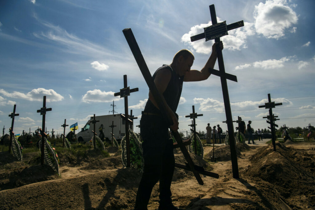 FILE PHOTO: A volunteer places a cross onto a grave of one of fifteen unidentified people killed by Russian troops, amid Russia's attack on Ukraine continues, during a burial ceremony in the town of Bucha, in Kyiv region, Ukraine September 2, 2022. REUTERS/Vladyslav Musiienko