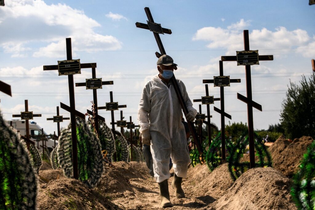 FILE PHOTO: A volunteer places a cross with a number to a grave of one of unidentified people killed by Russian troops, as Russia's attack on Ukraine continues, during a mass burial ceremony in the town of Bucha, in Kyiv region, Ukraine September 2, 2022. REUTERS/Vladyslav Musiienko/File Photo