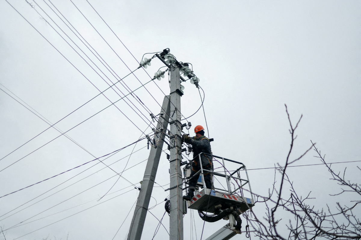 FILE PHOTO: An employee of power supplier repairs power lines in front of residential houses damaged by a Russian military strike, amid Russia's attack on Ukraine, in the town of Hlevakha, outside Kyiv, Ukraine January 26, 2023.  REUTERS/Valentyn Ogirenko/File Photo