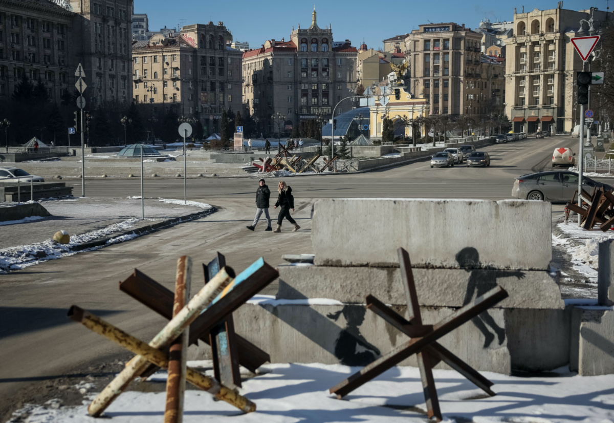 FILE PHOTO: People walk down a street near anti-tank constructions and a work of world-renowned graffiti artist Banksy as Russia's invasion of Ukraine continues, in central Kyiv, Ukraine February 8, 2023. REUTERS/Gleb Garanich/File Photo