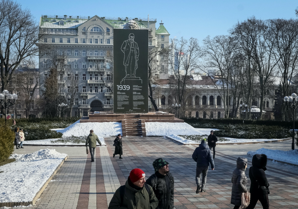People walk in a park near the monument of Ukrainian poet Taras Shevchenko covered with a protective construction to protect against shelling, amid Russia's invasion, in central Kyiv, Ukraine February 8, 2023.