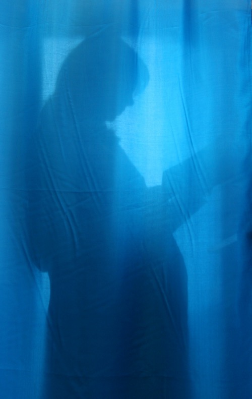 FILE PHOTO: A pregnant woman is seen through the curtain at a maternity hospital in the Ukrainian capital Kyiv, October 31, 2004. REUTERS/Mykhailo Markiv