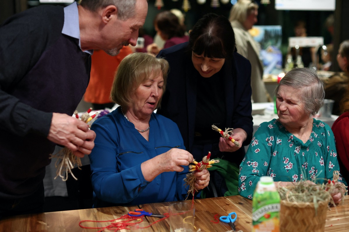 Ukrainian refugee Tatiana Potapova (2nd-R), 62, who is from Slabozhensky, shows a traditional bird she made from string, during an evening for pensioners to share Polish and Ukrainian traditions of Polish Fat Thursday and Ukrainian Stritennia, organised by the Senior Club at the Zustricz Foundation in Krakow, Poland, February 15, 2023. Larks, a symbol of spring, are made to decorate houses in some parts of Ukraine during Stritennia, which celebrates the meeting of winter and spring.  REUTERS/Kacper Pempel.