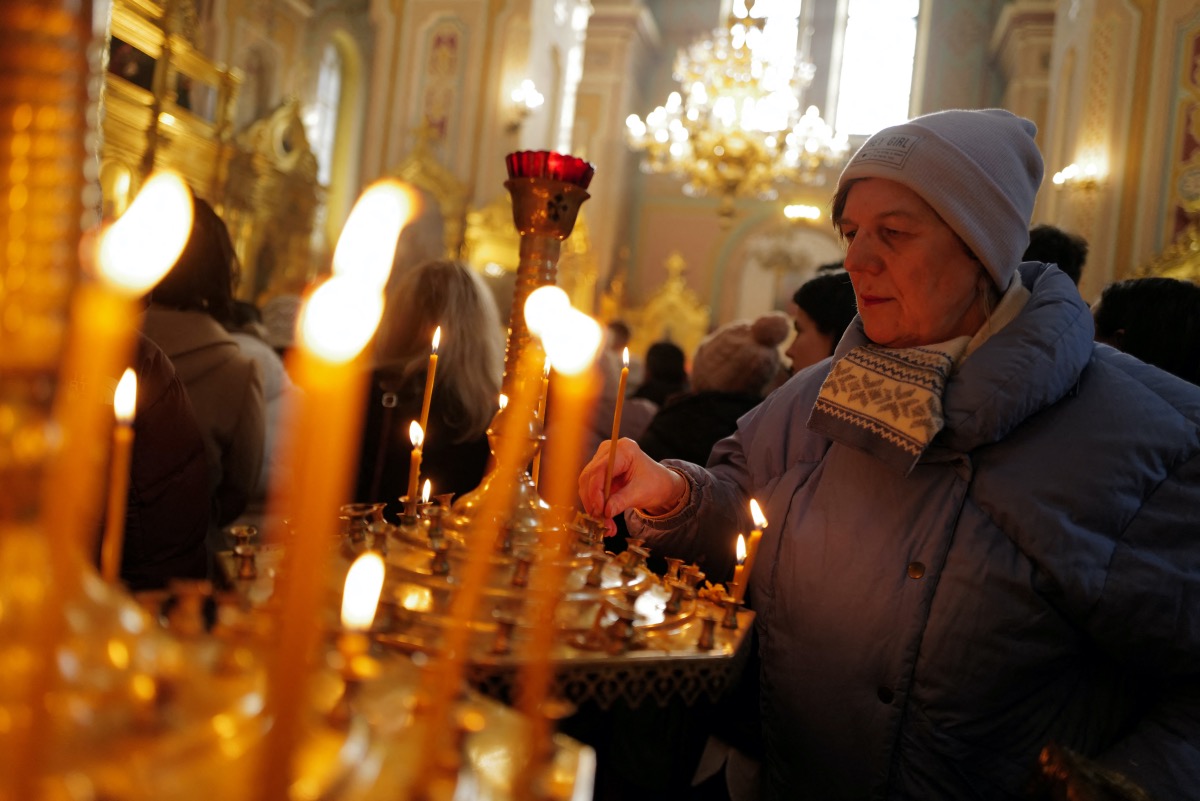 Ukrainian refugee Svitlana Skibina, 62, who is from Kharkiv, lights a candle as she attends mass at an Orthodox Church in Warsaw, Poland, February 12, 2023. 