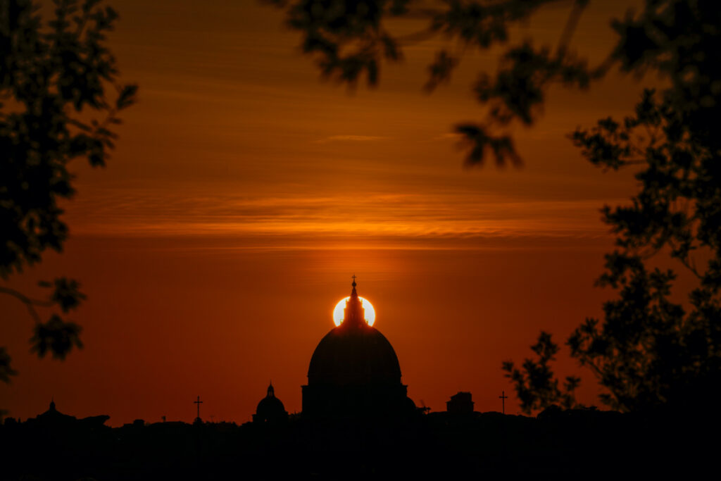 The sun sets behind the dome of St. Peter's Basilica, in Rome, on Feb. 20, 2023.