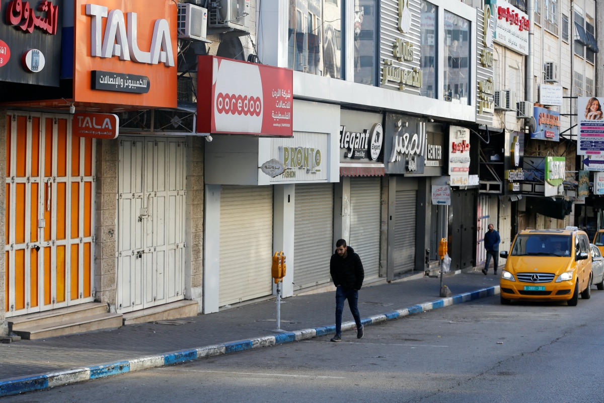 Palestinians walk next to closed shops during a strike, following the killing of several Palestinians including gunmen by Israeli troops during a raid, in Hebron in the Israeli-occupied West Bank February 23, 2023.