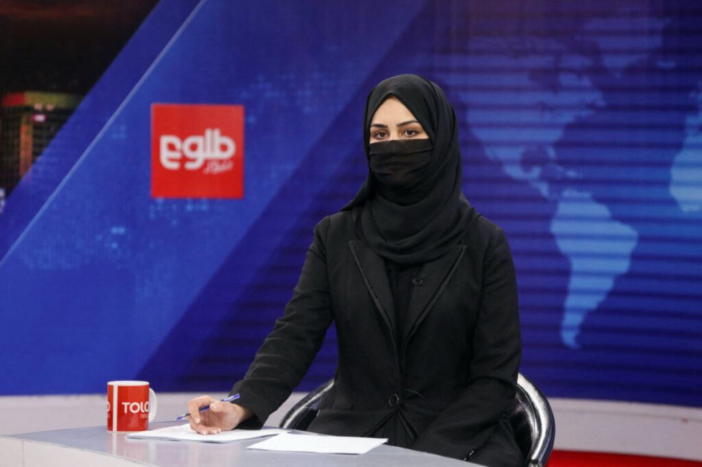 FILE PHOTO: A female presenter for Tolo News, Khatereh Ahmadi, while covering her face, works in a newsroom at Tolo TV station in Kabul, Afghanistan, May 22, 2022. REUTERS/Ali Khara