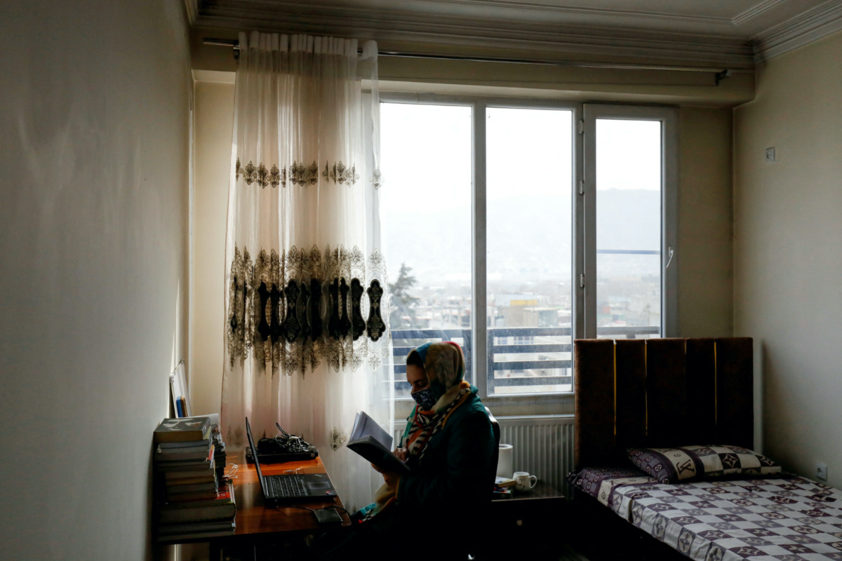 FILE PHOTO: Sana, an Afghan teacher, reads a book before starting an online class, at her house in Kabul, Afghanistan, February 28, 2023. REUTERS/Ali Khara