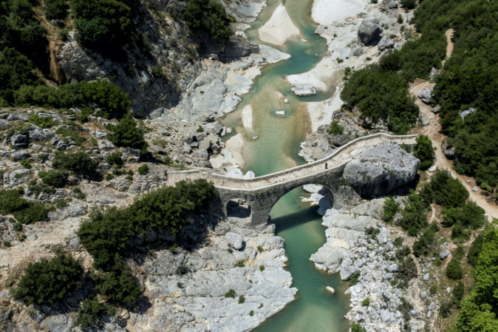 A person walks on the bridge at the Shushica tributary of the Vjosa River, in Brataj, Albania June 12, 2022.