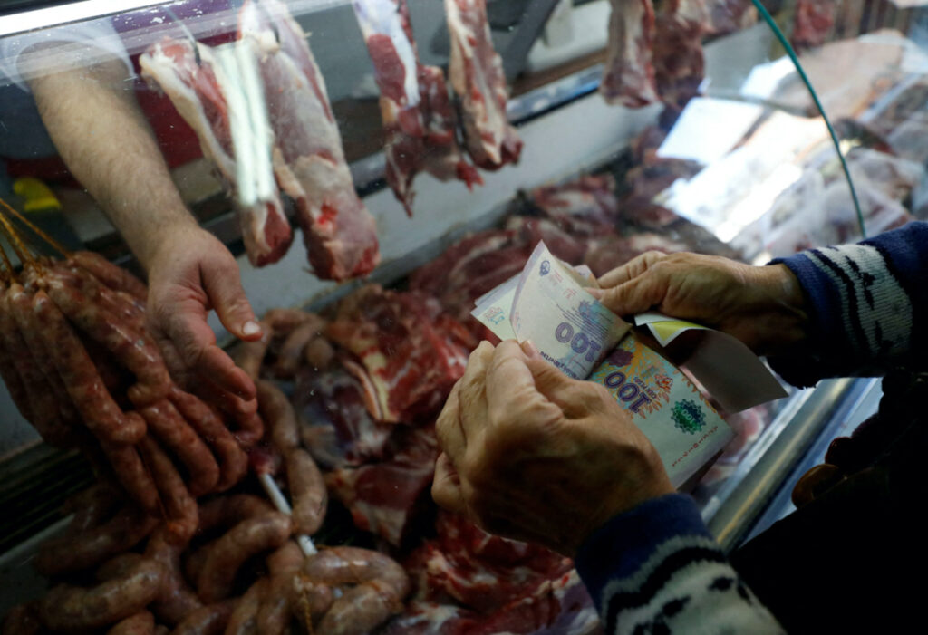 A customer counts money before paying at a butcher shop, as inflation in Argentina hits its highest level in years, causing food prices to spiral, in Buenos Aires, Argentina September 13, 2022.