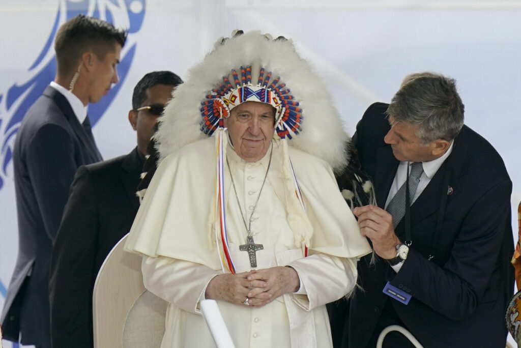 FILE - Pope Francis dons a headdress that was gifted to him during a visit with Indigenous peoples at Maskwaci, the former Ermineskin Residential School, Monday, July 25, 2022, in Maskwacis, Alberta. The Vatican Museums officially reopened its African and American ethnographic collections Thursday, March 16, 2023, by showcasing intricately restored Rwandan raffia screens that were sent by Catholic missionaries to the Vatican for a 1925 exhibit. (AP Photo/Eric Gay, File)