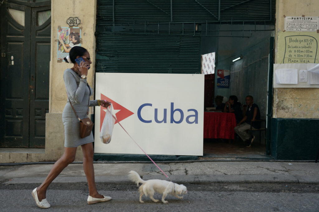 A woman walks a dog past a polling station during the legislative elections in Havana, Cuba, on 26th March, 2023.