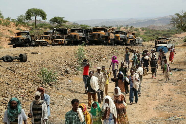 Villagers return from a market to Yechila town in south central Tigray walking past scores of burned vehicles, in Tigray, Ethiopia, on 10th July, 2021.