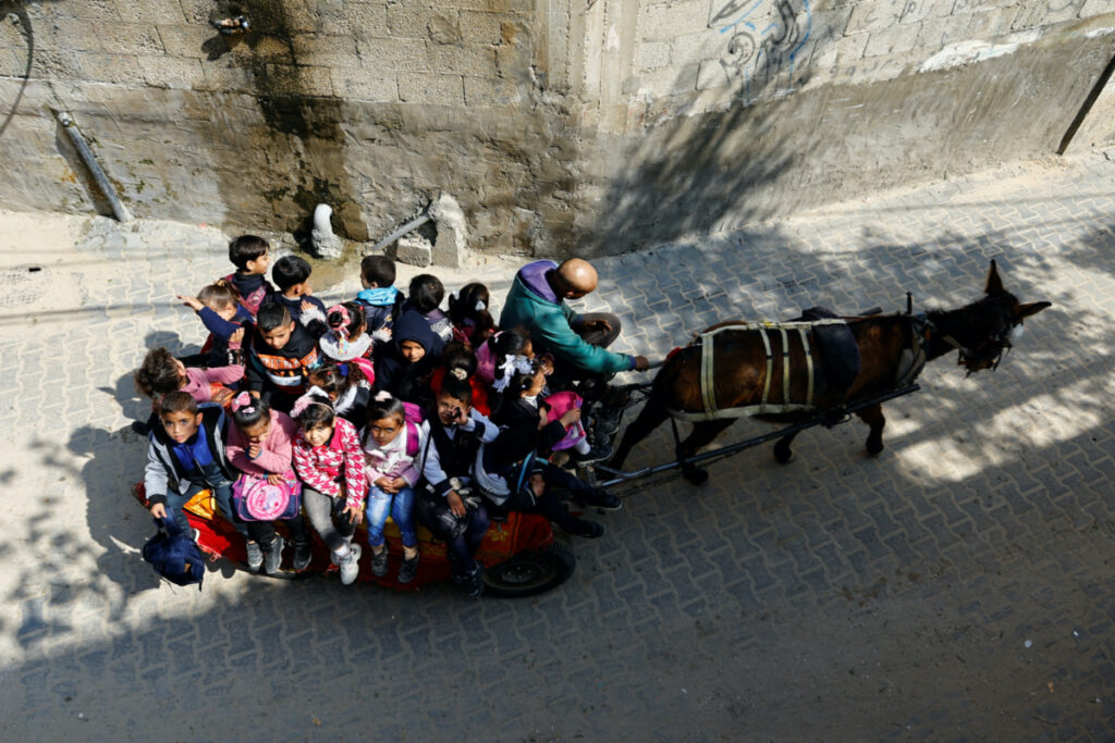 Palestinian man Loay Abu Sahloul offers to some students a low-cost donkey-cart ride to kindergarten in Khan Younis, southern Gaza Strip, February 27, 2023. REUTERS/Ibraheem Abu Mustafa