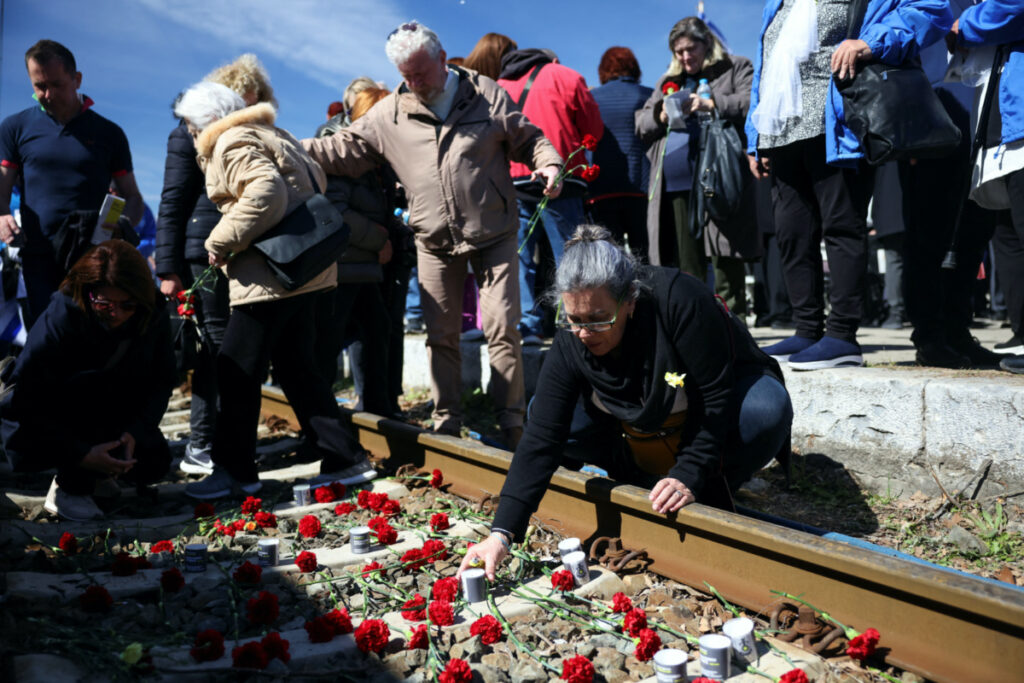 People leave candles and flowers on train tracks during a memorial marking the 80th anniversary of the first deportation of Jews from Thessaloniki to Auschwitz, in Thessaloniki, Greece March 19, 2023. REUTERS/Alexandros Avramidis