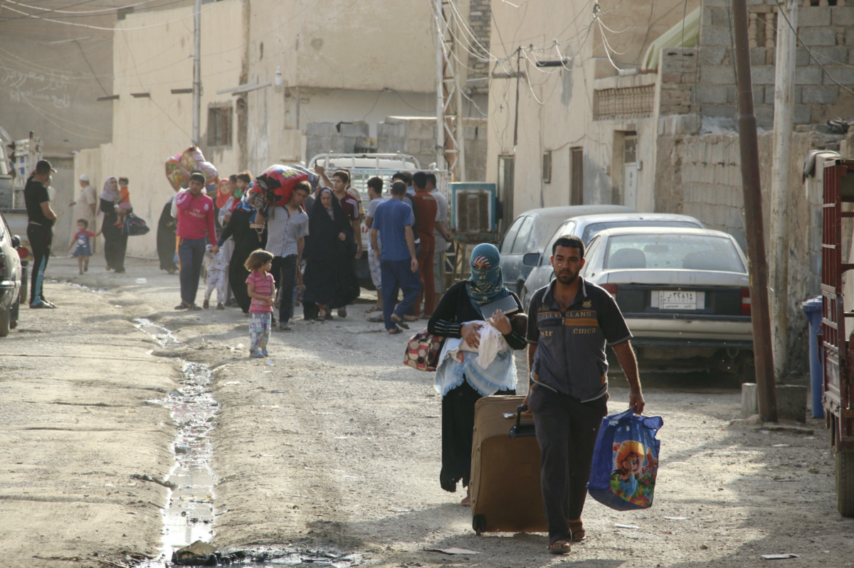 FILE PHOTO: Sunni people fleeing violence walk down a road in the city of Ramadi, Iraq May 15, 2015. Islamic State militants raised their black flag over the local government compound in the Iraqi city of Ramadi on Friday and claimed victory through mosque loudspeakers after overrunning most of the western provincial capital. The insurgents attacked Ramadi overnight using six suicide car bombs to reach the city centre, where the Anbar governorate compound is located, police sources said. REUTERS/Stringer/File Photo