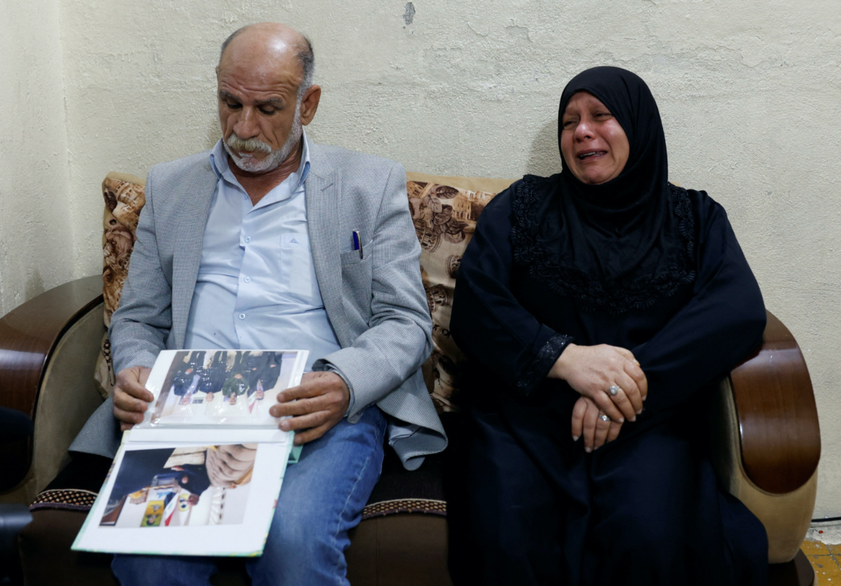 Majid Mohammed looks at pictures of his son who disappeared after the Camp Speicher massacre in 2014, where some of the hundreds of Iraqi military recruits who were abducted from Camp Speicher by Islamic State militants in June 2014 are believed to have been murdered, as his wife, Nadia Jasim, reacts during an interview with Reuters, in Baghdad, Iraq, February 4, 2023.