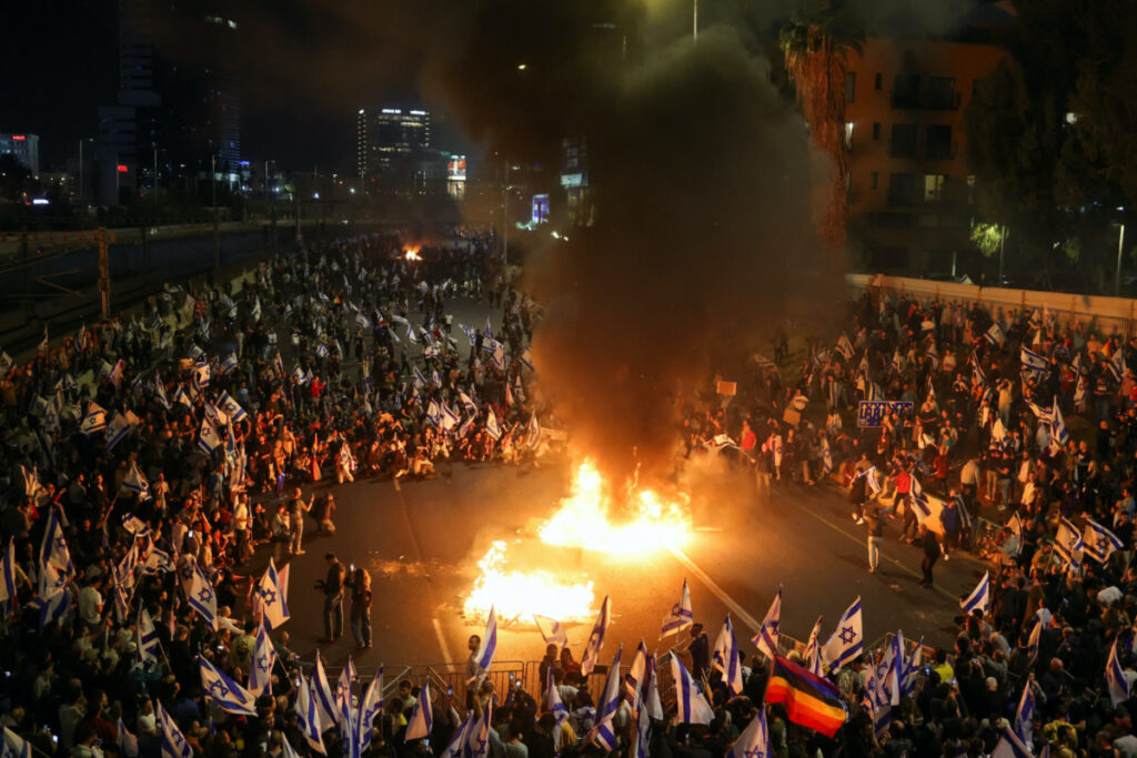 Fire burns as people attend a demonstration after Israeli Prime Minister Benjamin Netanyahu dismissed the defense minister and his nationalist coalition government presses on with its judicial overhaul, in Tel Aviv, Israel, on 27th March, 2023