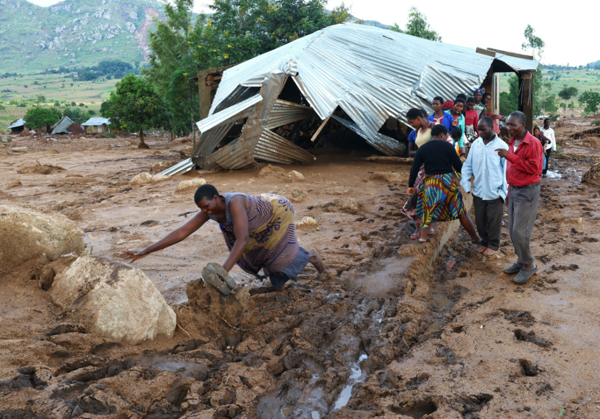 Locals of Mtauchira village walks past a home which was damage by a mudslide in the aftermath of Cyclone Freddy in Blantyre, Malawi, March 16, 2023.