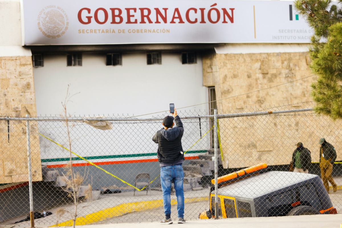 A migrant records a video with a phone outside the National Migration Institute (INM) building, after a fire broke out late on Monday at a migrant holding center, in Ciudad Juarez, Mexico, March 28, 2023. REUTERS/Jose Luis Gonzalez