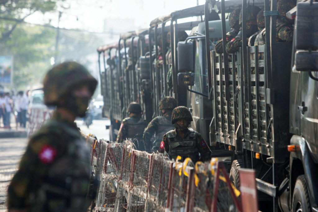 FILE PHOTO: Soldiers stand next to military vehicles as people gather to protest against the military coup, in Yangon, Myanmar, February 15, 2021. REUTERS/Stringer/File Photo