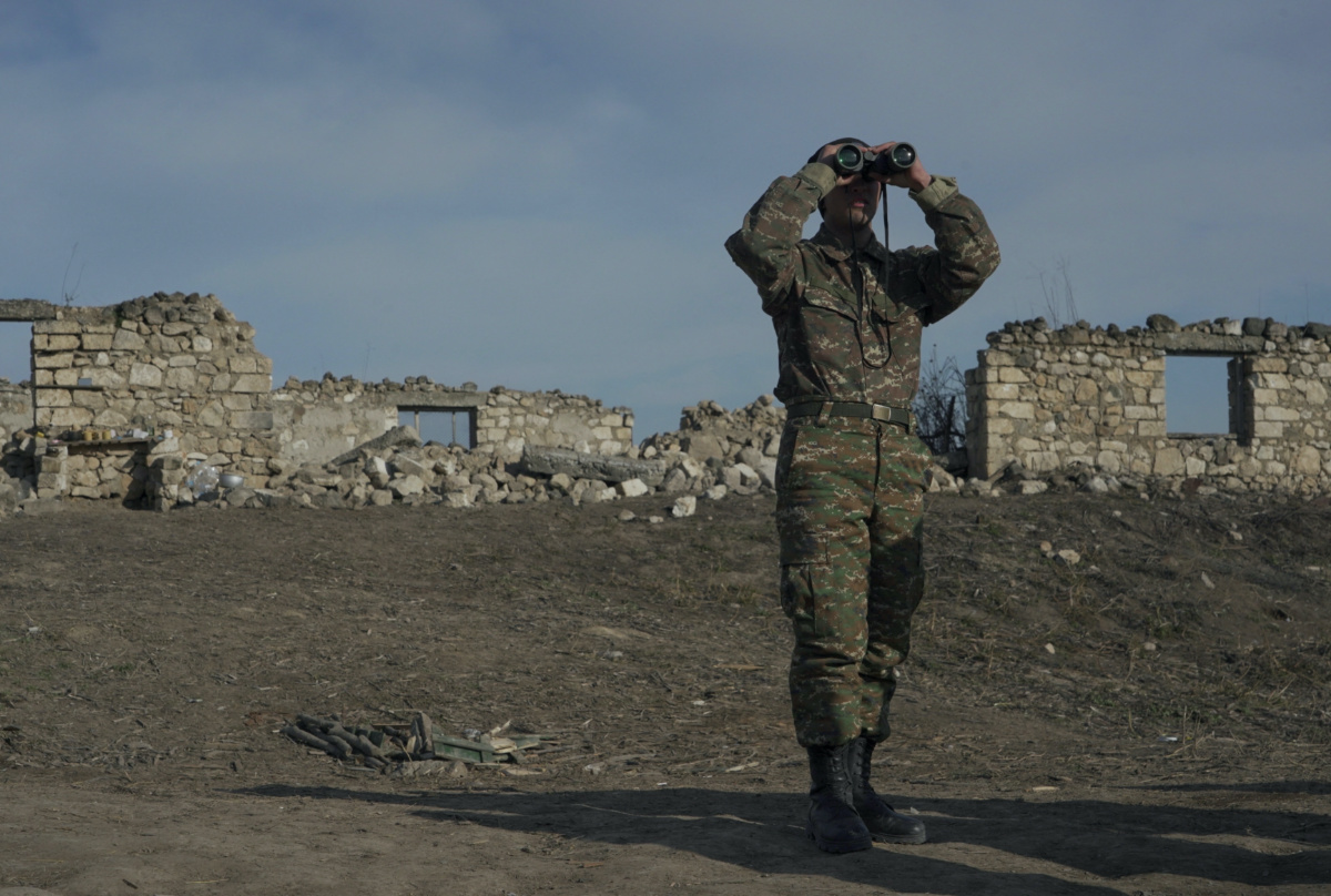 An ethnic Armenian soldier looks through binoculars as he stands at fighting positions near the village of Taghavard in the region of Nagorno-Karabakh, January 11, 2021. 