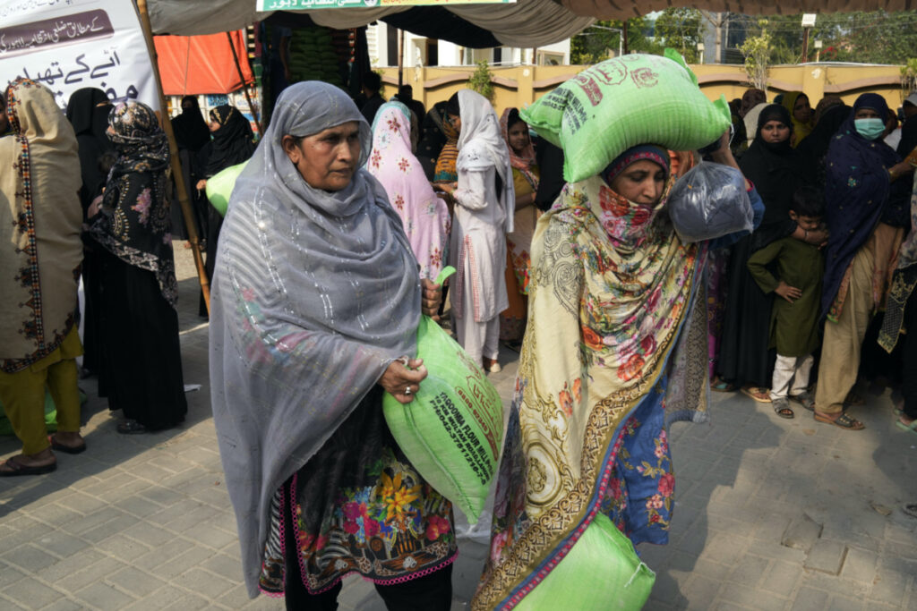 Women leave while others wait their turn to get a free sack of wheat flour at a distribution point, in Lahore, Pakistan, Thursday, on 30th March, 2023