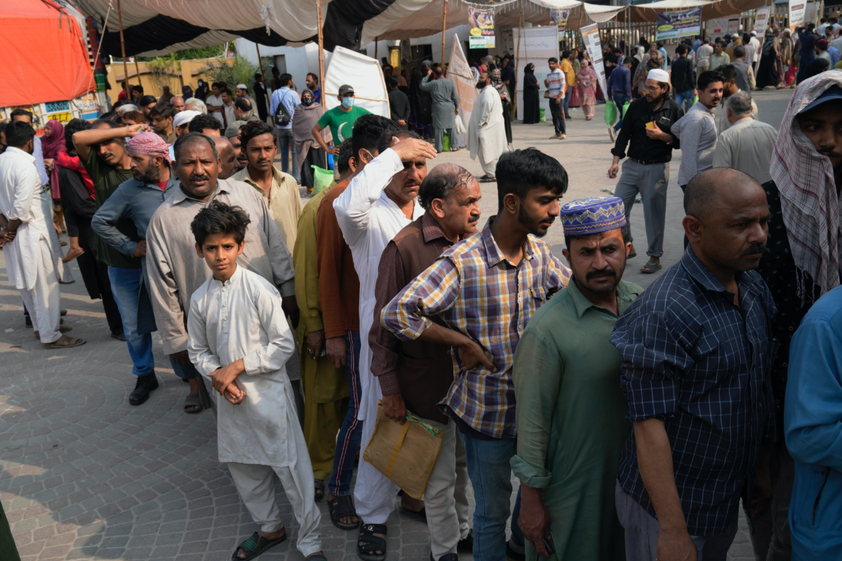 People gather and wait their turn to get a free sack of wheat flour at a distribution point, in Lahore, Pakistan, Thursday, 30th March, 2023. 