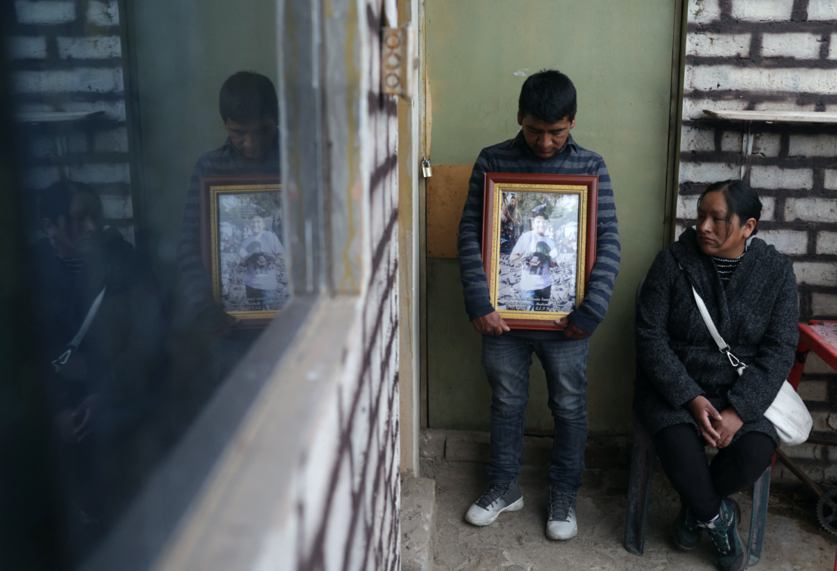 Vera Lucia Samillan sits while her brother Juan holds a photo of their brother Marco Antonio Samillan, one of the victims killed during latest protests against Peru's President Dina Boluarte, as they mourn at their home in Juliaca, in Puno region, Peru February 8, 2023. REUTERS/Pilar Olivares