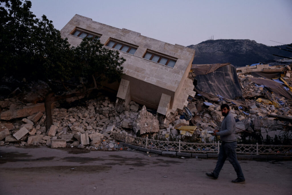 A man walks by a collapsed building and rubble, in the aftermath of a deadly earthquake, in Antakya, Hatay province, Turkey, February 21, 2023.