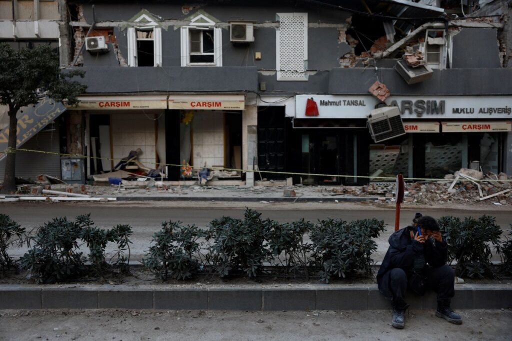 Hatice Yigit, 57, speaks on the phone as she waits for news on the search for the gold and money she saved for her daughter's engagement in the remains of her collapsed home after a deadly earthquake in Antakya, Hatay province, Turkey, March 1, 2023.